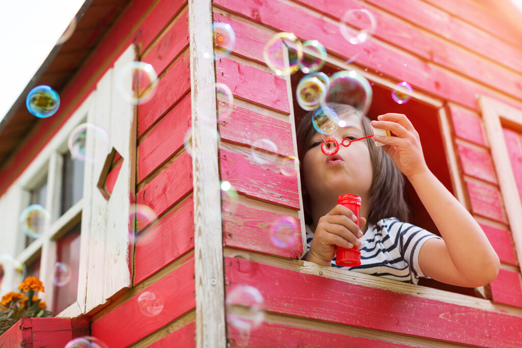 Boy blowing bubbles in a wooden playhouse